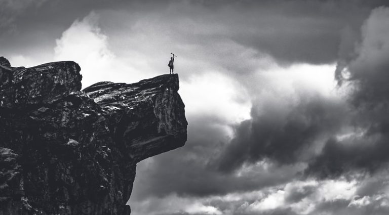 grayscale photo of rocky mountain under cloudy sky