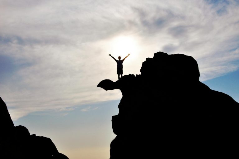 Silhouette Photography of Person Standing on Rock